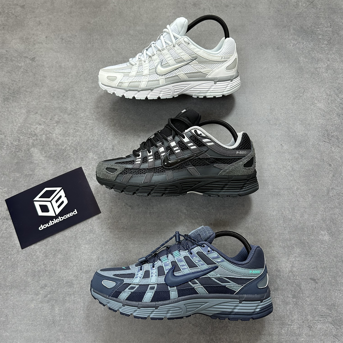Three Nike P-6000 trainers in white, black and navy colourways photographed at Double Boxed